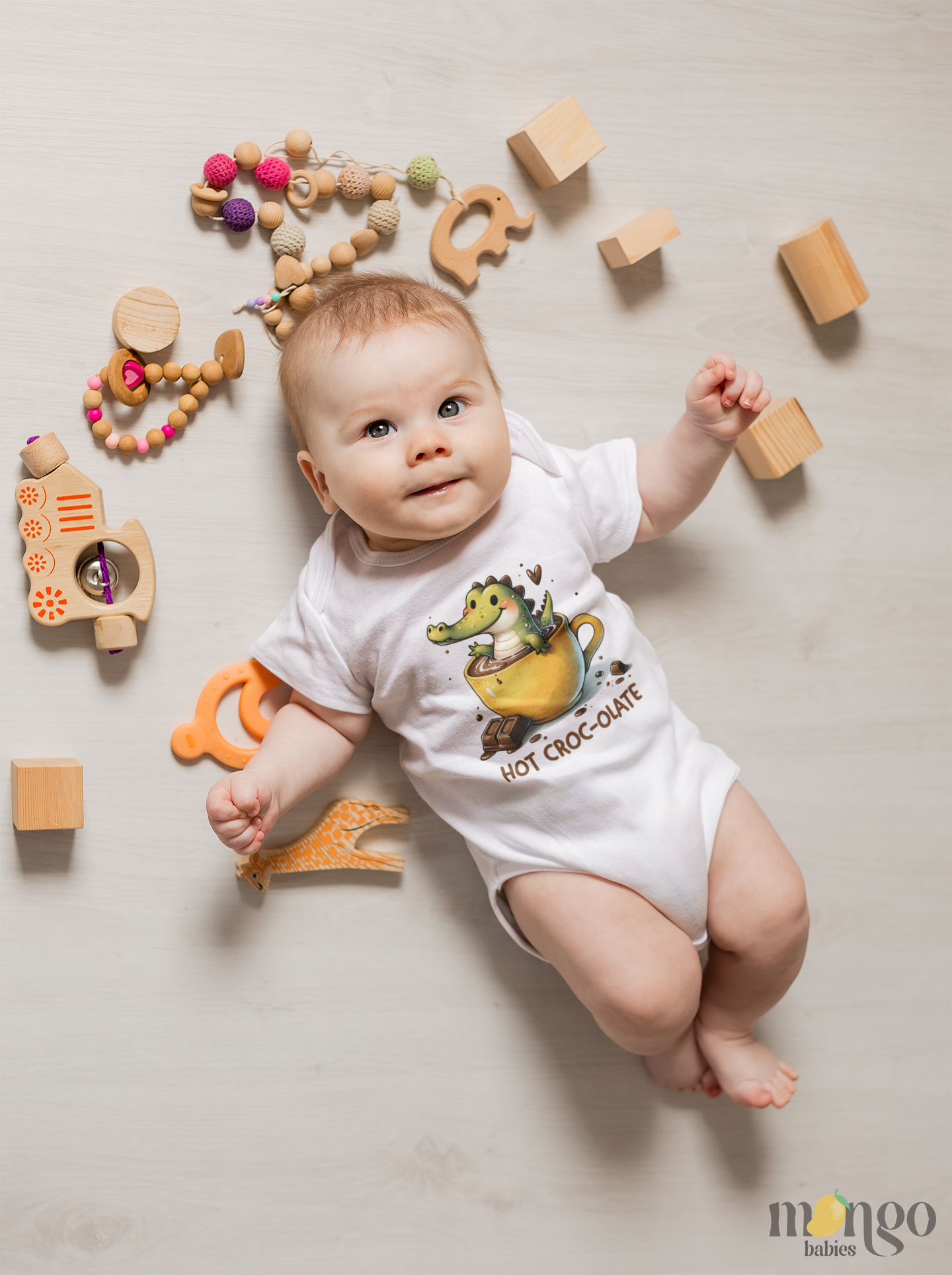 Cute crocodile sitting in a chocolate milk cup with text “HOT CROCO-LATE” printed on baby bodysuit, kids t-shirt, sweater, and adult unisex shirt.