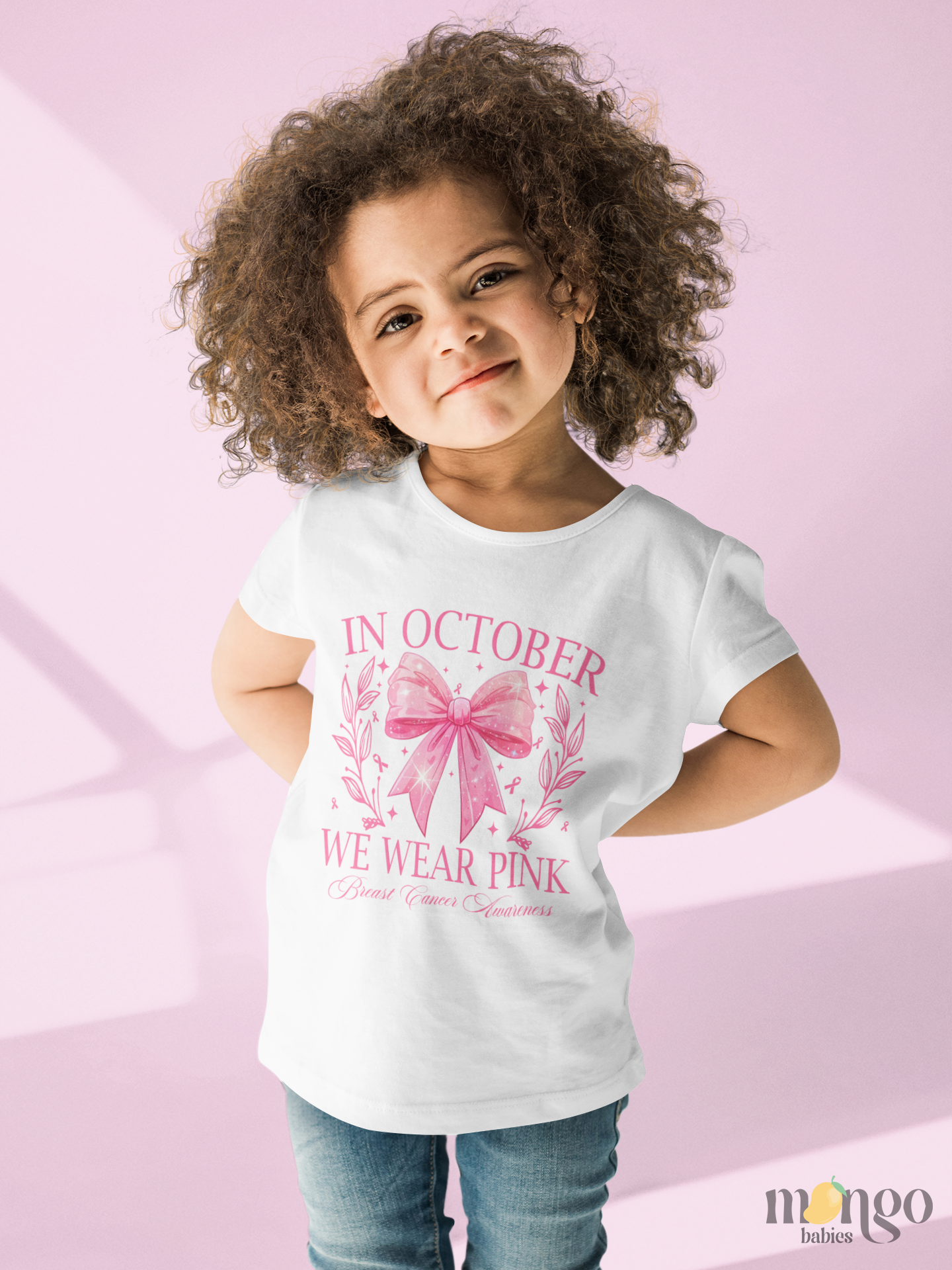 Pink bow shirt with “In October We Wear Pink” text, available in baby bodysuits and kids’ T-shirts for breast cancer awareness.