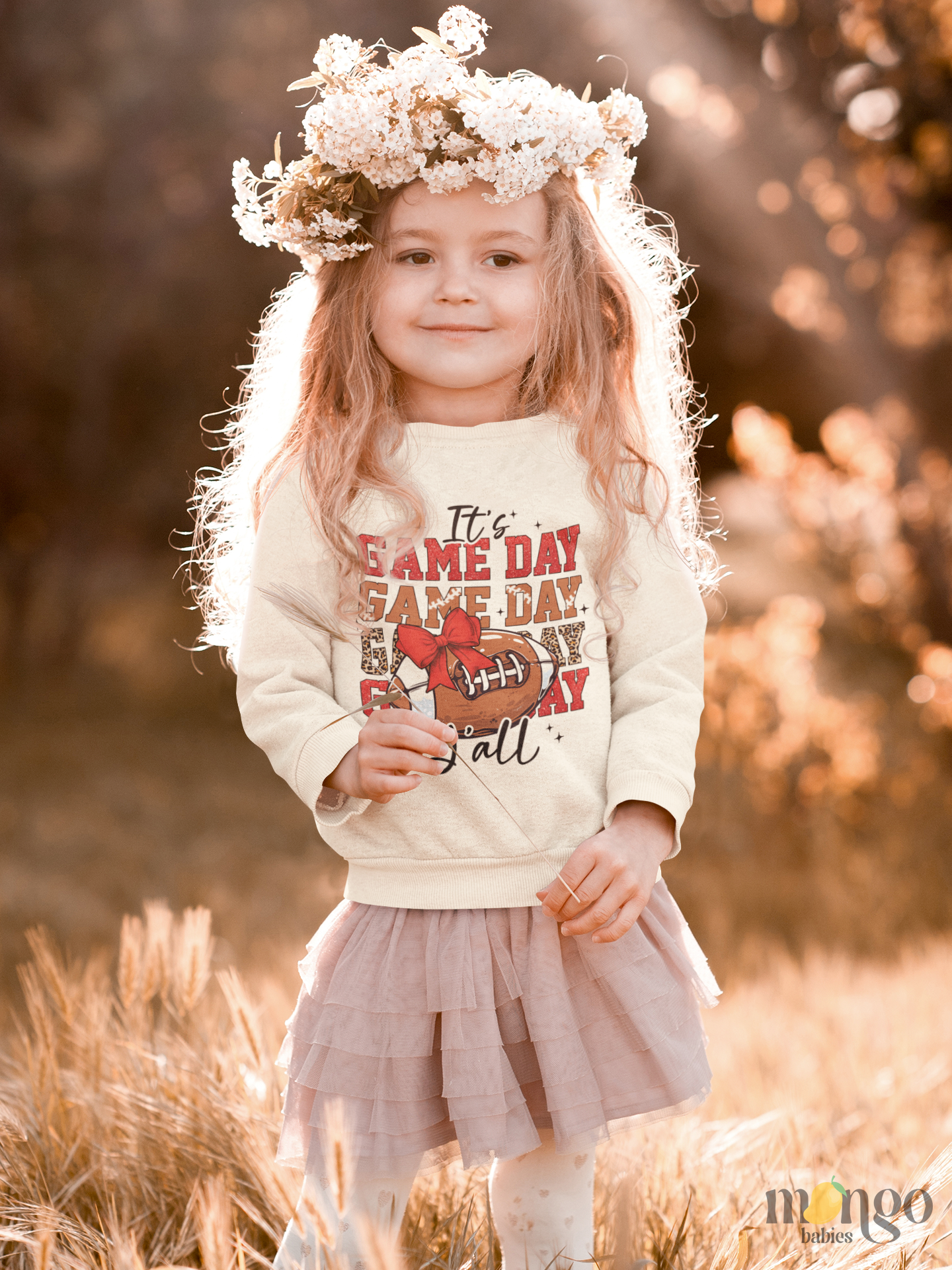 Football graphic with red bow and “It’s Game Day Y’all” printed on baby bodysuit, kids’ t-shirt, sweatshirt, and unisex adult shirt.