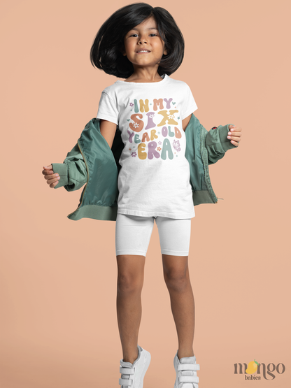 Retro pastel kids’ T-shirt with “In My Six Year Old Era” text, flowers, and butterflies. Soft cotton, perfect birthday shirt for six-year-olds.
