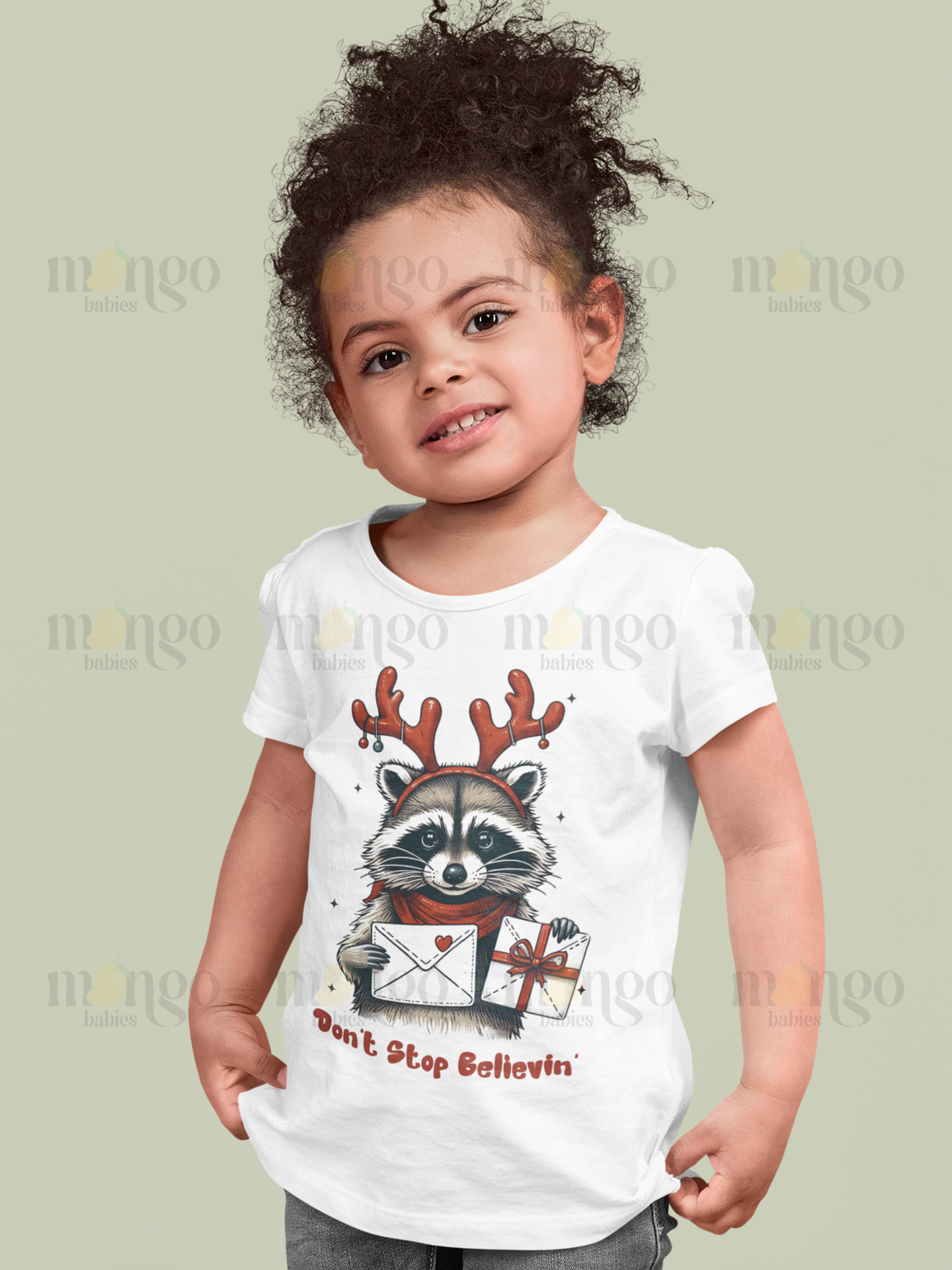 Christmas raccoon shirt with "Don’t Stop Believing" text, available in baby, kids, and adult sizes.
